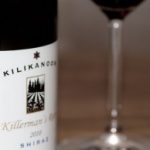 Kilikanoon Shiraz Weinflasche mit Etikett neben gefülltem Rotweinglas auf Holztisch