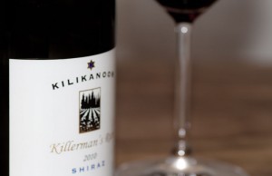Kilikanoon Shiraz Weinflasche mit Etikett neben gefülltem Rotweinglas auf Holztisch