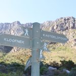 Wegweiser in felsiger Berglandschaft mit Schildern "Kloofnek" und "Kasteelspoort" für Wanderrouten zum Tafelberg
