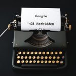 Eine alte mechanische Schreibmaschine mit eingelegtem Blatt Papier, auf dem die Google-Fehlermeldung ‚403 Forbidden‘ zu lesen ist. Das Bild symbolisiert den Kontrast zwischen analoger Technik und digitalen Barrieren – oder die Ironie, wenn selbst ein Suchmaschinenriese wie Google auf einer Vintage-Schreibmaschine ‚gesperrt‘ wird
