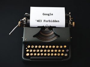Eine alte mechanische Schreibmaschine mit eingelegtem Blatt Papier, auf dem die Google-Fehlermeldung ‚403 Forbidden‘ zu lesen ist. Das Bild symbolisiert den Kontrast zwischen analoger Technik und digitalen Barrieren – oder die Ironie, wenn selbst ein Suchmaschinenriese wie Google auf einer Vintage-Schreibmaschine ‚gesperrt‘ wird