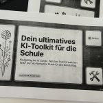 Gedrucktes KI-Toolkit für Schulen mit Symbolen für Online-Status und Tools auf schwarzem Hintergrund neben Tastatur