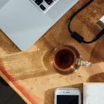 Arbeitsplatz mit MacBook, iPhone und Kaffee auf Korkunterlage – Schreibtisch für digitale Arbeit und KI-Nutzung