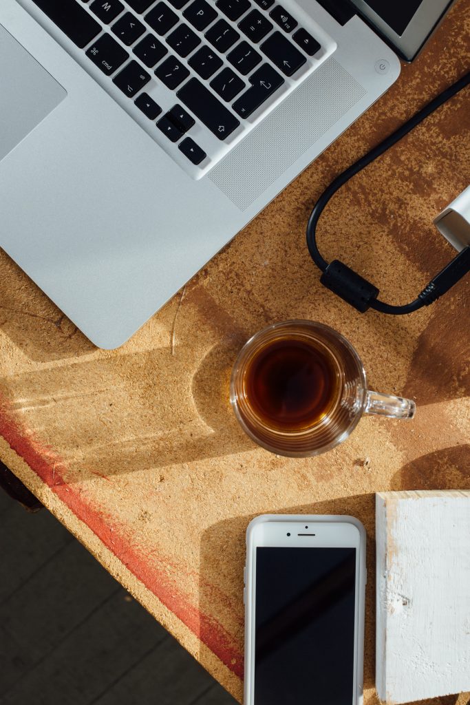 Arbeitsplatz mit MacBook, iPhone und Kaffee auf Korkunterlage – Schreibtisch für digitale Arbeit und KI-Nutzung