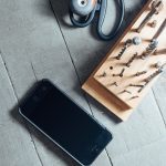 Werkstatt-Arbeitsplatz mit Smartphone, Schleifer, Werkzeugboard mit Bits und Schrauben auf grauem Holztisch